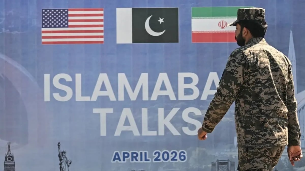 A Pakistani Ranger walks past a billboard for the US-Iran peace talks in Islamabad