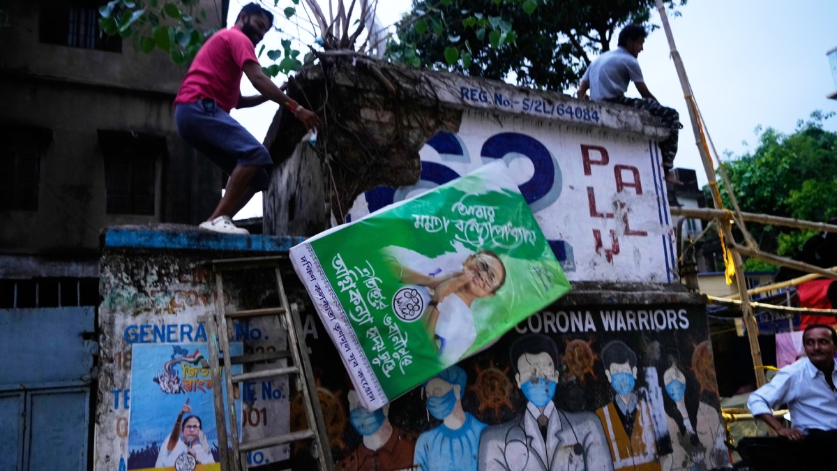 মমতা বন্দ্যোপাধ্যায়ের তৃণমূল কংগ্রেস সংখ্যাগরিষ্ঠতা অর্জনে ব্যর্থ হওয়ার খবরে এক সমর্থক তার ছবি সম্বলিত নির্বাচনি বিলবোর্ড সরিয়ে ফেলছেন। ছবি: এপি