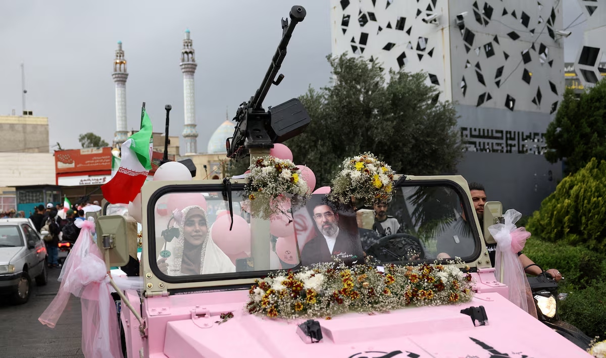 An Iranian couple arrive on a military vehicle during a public wedding ceremony