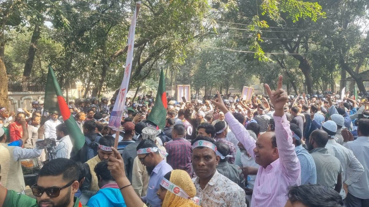 Government employees stand in front of 'Yamuna' after breaking barricades, tear gas fired