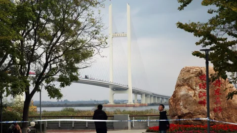বৃহস্পতিবার চীনের লিয়াওনিং প্রদেশের দানদংয়ে নিউ ইয়ালু রিভার ব্রিজের উদ্বোধনী অনুষ্ঠানের আগে ব্যারিকেড দিয়ে ঘিরে রাখা এলাকায় পাহারা দিচ্ছেন নিরাপত্তাকর্মীরা। সেতুটি চীনের দানদং নিউ জোনের সঙ্গে উত্তর কোরিয়ার সিনুইজুকে যুক্ত করেছে। ছবি: রয়টার্স