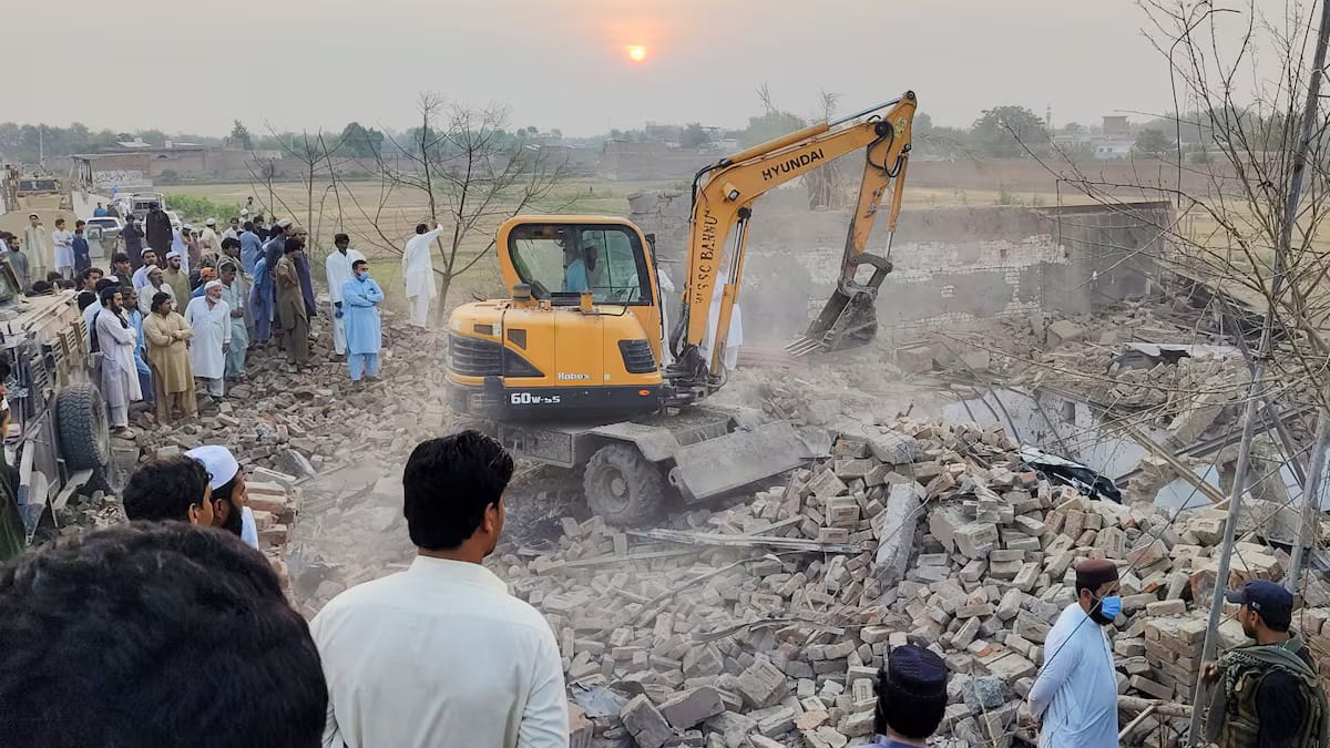 হামলায় ক্ষতিগ্রস্ত পুলিশ চৌকির ধ্বংসস্তূপ সরাতে ভারী যন্ত্রপাতি ব্যবহার করা হচ্ছে। এ সময় সেখানে জড়ো হন স্থানীয় বাসিন্দারা। ছবি: রয়টার্স