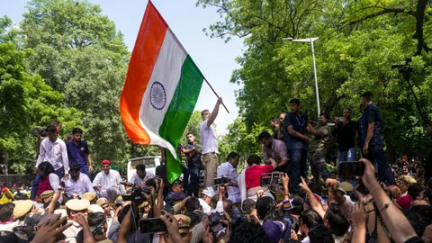 মঙ্গলবার নয়াদিল্লিতে সিইসি জ্ঞানেশ কুমারের পদত্যাগের দাবিতে সংসদ ভবন থেকে ভারতের নির্বাচন কমিশনের কার্যালয় অভিমুখে প্রতিবাদ মিছিল করে বিরোধী জোট। মিছিলটি আটকে দিলে পুলিশ ব্যারিকেডের ওপর দাঁড়িয়ে জাতীয় পতাকা নাড়ছেন বিরোধীদলীয় নেতা রাহুল গান্ধী। ছবি: পিটিআই