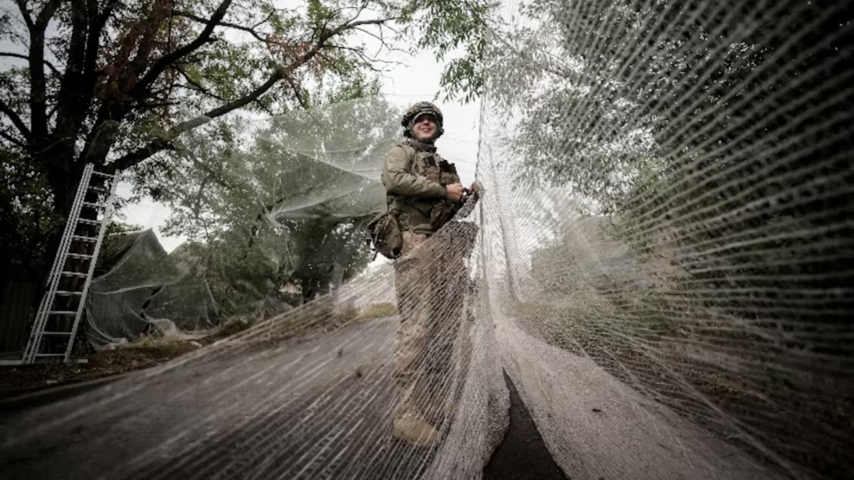 Ukrainian Armed Forces member installs anti-drone nets over a road, amid Russia's attack on Ukraine