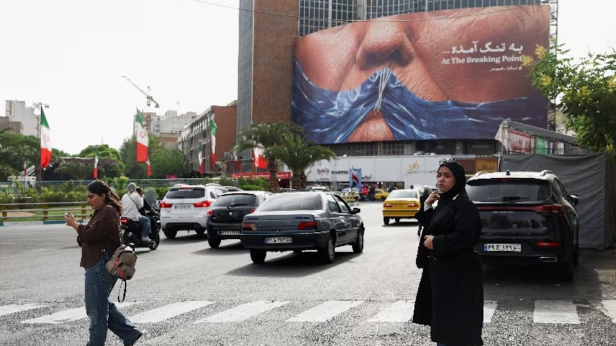 A woman walks past an anti-U.S. billboard depicting U.S. President Donald Trump and the Strait of Hormuz, in Tehran